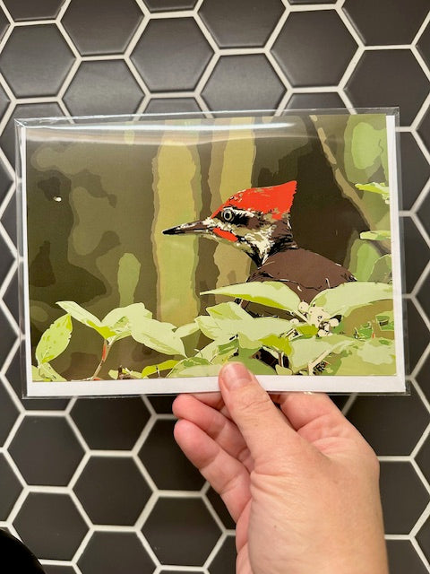 Card with a bird design held by a hand against a tiled wall background